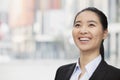 Close-up portrait of smiling, confident, young businesswoman with a ponytail looking up, outdoors with skyscrapers in the Royalty Free Stock Photo