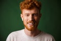 Close-up portrait of smiling curly redhead man, listening to mus