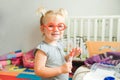 Close up portrait of smiling cute blondy toddler baby girl playing doctor with plastic toy glasses and syringe at home, in child r Royalty Free Stock Photo