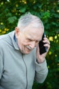 Close-up portrait of a smiling elderly man using a mobile phone. Active optimistic old age. Communication in old age Royalty Free Stock Photo