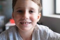 Close-up portrait of smiling elementary schoolboy sitting at desk in classroom