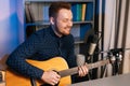 Close-up portrait of smiling guitarist singer man playing on acoustic guitar and singing into microphone recording song Royalty Free Stock Photo