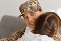 Close up portrait of smiling happy caucasian woman wearing camouflage uniform and cap posing with her daughter, looking at camera Royalty Free Stock Photo