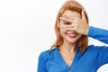 Close up portrait of smiling happy woman covers her eyes, peeks through fingers, intrigued by surprise, stands over