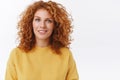 Close-up portrait smiling happy woman with red curly hair in yellow sweater, looking camera with delighted, pleased