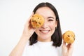 Close up portrait of smiling korean woman, shows tasty cupcakes, eating cake and looking happy, pastry and bakery Royalty Free Stock Photo