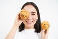 Close up portrait of smiling korean woman, shows tasty cupcakes, eating cake and looking happy, pastry and bakery Royalty Free Stock Photo