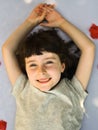 Close up portrait of smiling little girl while rose petals fall on her Royalty Free Stock Photo