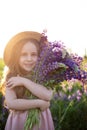 Close up portrait of a smiling little girl in a straw hat and with a large bouquet of lupins. A child girl in a field of lupines. Royalty Free Stock Photo