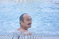 Smiling mature asian man in outdoor thermal pool with hydromassage. Royalty Free Stock Photo