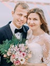 The close-up portrait of the smiling newlyweds. The bride is holding the wedding bouquet consisted of white and pink Royalty Free Stock Photo