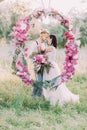 The close-up portrait of the smiling newlyweds holding the bouquets of flowers and standing behind the wedding peonies Royalty Free Stock Photo