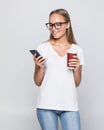 Close up portrait of a smiling pretty woman in hat holding mobile phone  over gray background Royalty Free Stock Photo