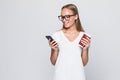 Close up portrait of a smiling pretty woman in hat holding mobile phone  over gray background Royalty Free Stock Photo