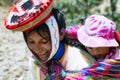 Close up portrait of a smiling Quechua woman dressed in colorful traditional handmade outfit and carrying her baby in a sling Royalty Free Stock Photo
