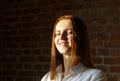 Close-up portrait of a smiling red-haired girl against the background of loft space, sunlight Royalty Free Stock Photo