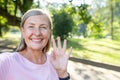 Close-up portrait of a smiling senior gray-haired woman standing outside in a park, talking and greeting on a mobile Royalty Free Stock Photo
