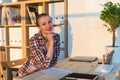 Close-up portrait of smiling woman reading paper at her workplace, looking camera on sunny day in light office room. Royalty Free Stock Photo