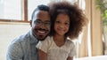Portrait of happy biracial dad and daughter posing at home
