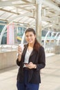 Close up portrait smiling young Asian woman in casual shirt long hair standing and holding coffee cup and mobile phone Royalty Free Stock Photo