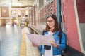 Close up portrait smiling young Asian woman in white dress holding a map smiling and looking at camera standing side train stair Royalty Free Stock Photo