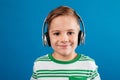 Close-up portrait of smiling young boy listening music by earphone Royalty Free Stock Photo