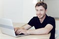 Close up portrait of a smiling young caucasian man working at home on laptop sitting at desk. Royalty Free Stock Photo
