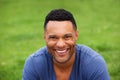 Close up smiling young man sitting outdoors against green grass Royalty Free Stock Photo