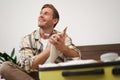 Close up portrait of smiling young man, writing down notes, holding pen and notebook, check-list of items in suitcase Royalty Free Stock Photo