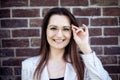 Close-up portrait of a smiling young woman with glasses against a brick wall Royalty Free Stock Photo