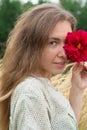 Close up portrait of a smiling young woman holding scarlet red colored blossoming dahlia