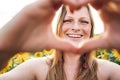 Close up portrait of smiling young woman making heart shape with her hands at sunflower field Royalty Free Stock Photo