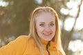 Close up portrait of smiling young woman with red hair in yellow jacket on sunny day. Warm light Royalty Free Stock Photo