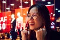 Close-up portrait of smiling young woman with reflection on glasses looking on shop windows. Big sales in shopping mall.