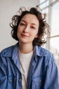 Close-up portrait of smiling young woman with short curly hair in blue shirt looking at camera Royalty Free Stock Photo