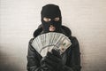 Close up portrait of sneaky burglar with black mask, gloves counting money on white background. focus on money. Royalty Free Stock Photo