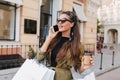 Close-up portrait of spectacular fashionista girl drinking coffee in city. Outdoor photo of joyful shopaholic woman