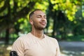 Close-up portrait of sportsman in park, hispanic man jogging in park with eyes closed breathing fresh air and resting Royalty Free Stock Photo