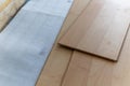 A close up portrait of stacked wood imitation laminate floorboards lying on some sound isolation ready to be installed to create a