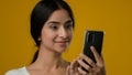 Close up portrait in studio Indian ethnic 20s woman girl female lady looking at smartphone screen browsing typing Royalty Free Stock Photo