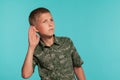 Close-up portrait of a blonde teenage boy in a green shirt with palm print posing against a blue studio background Royalty Free Stock Photo