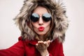 Close up portrait of stylish cool woman blowing red lips sending sweet air kiss stretching hand for taking selfie Royalty Free Stock Photo