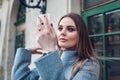 Close up portrait of stylish woman looking at hand mirror outdoors checking makeup. Spring female fashion Royalty Free Stock Photo
