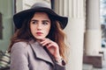 Close up portrait of stylish young woman wearing hat grey coat outdoors. Spring fashion female retro accessories outfit Royalty Free Stock Photo