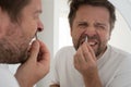 suffering bearded man plucking out his nose hair.