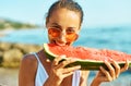 Close-up portrait summer woman in red glasses funny eating watermelon, bites him with pleasure