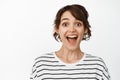 Close up portrait of surprised and amazed brunette woman, gasping fascinated, looking astonished, standing against white