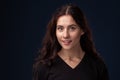 Close-up portrait of a beautiful brunette with curly hair and professional make-up posing on a black background. Royalty Free Stock Photo