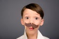 Close up portrait of surprised funny schoolboy holding paper mustache Royalty Free Stock Photo