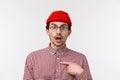 Close-up portrait surprised young hipster guy in glasses and beanie staring with disbelief, pointing himself indecisive